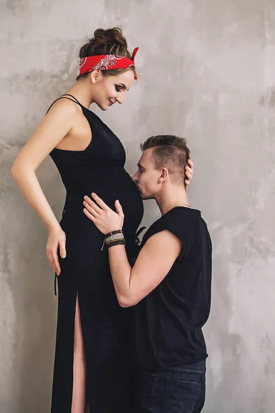 Frumos bărbat elegant și femeie însărcinată cu burtă mare în haine negre se uită unul la celălalt și se bucură de ei înșiși, viitoarele chirie, așteptând un copil fotografii de stoc fără drepturi de autor