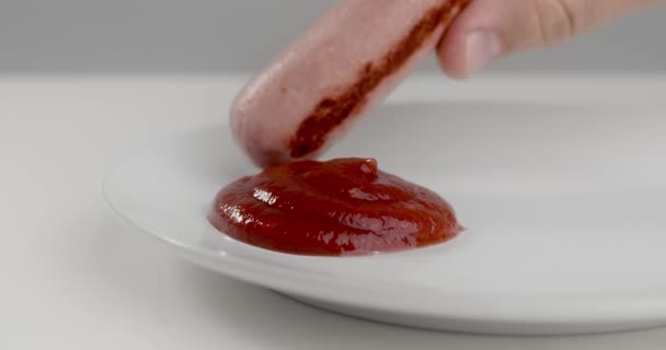 Sausage is dipped in ketchup in slow motion, tomato ketchup with meat, sausage on the plate with hot sauce, 4k DCI 120fps Prores HQ — ストック動画