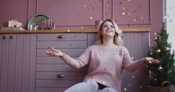 Mooie vrouw in warme trui gooit glimmende confetti in slow motion, kerst sfeer, vallende gouden confetti, oudejaarsavond, kerst selebration, 4k Dci 120fps Prores Hq — Stockvideo