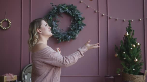 Mujer atractiva en suéter lanza una bola de navidad en cámara lenta, decorando el árbol de navidad, acogedor ambiente casero de año nuevo, Full HD 120fps Prores HQ — Vídeo de stock