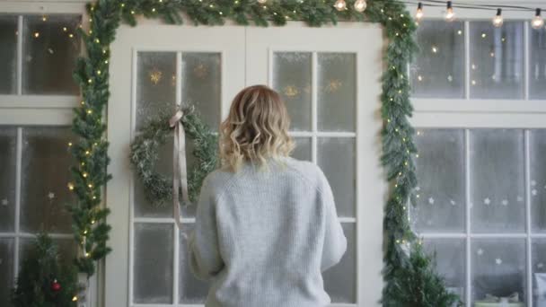 Femme en pull chaud jette décore les portes principales avec couronne de Noël, décoration de la maison de Noël, atmosphère confortable nouvelle année à la maison, Full HD 120fps Prores HQ — Video