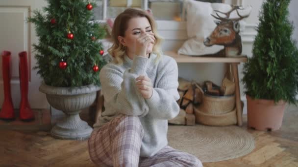 Европейская молодая привлекательная женщина в теплом свитере сидит в скандальном интерьере, уютной домашней атмосфере и новогодних украшениях, Full HD 120fps — стоковое видео