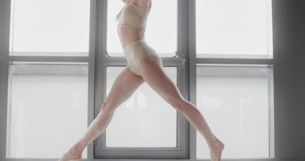 Aantrekkelijke jonge blonde vrouw zit op een touw in slow motion op de vensterbank van yoga studio, flexibele vrouw doet acrobatische en plastische oefeningen, yoga en stretching, 4k Dci 60p Prores 422 — Stockvideo