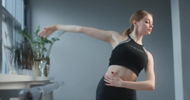 Atrakcyjna młoda kobieta rozciąga się i ćwiczy w pobliżu baletu w sali tanecznej, seksowna tancerka na zajęciach, klasyczne ćwiczenia baletowe, gimnastyka elastycznego kobiecego ciała, 4k Dci 60p — Wideo stockowe