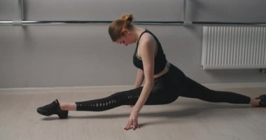 Çekici genç kadın bale makinesinin yanında yavaş çekimde sicim üzerinde oturuyor, esnek kadın akrobatik ve plastik egzersizler yapıyor, yoga ve esneme, 4k DCI 60p Prores 422