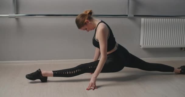 Attraktiv ung kvinna sitter på ett garn i slow motion nära balettmaskinen, flexibel kvinna gör akrobatiska och plastiska övningar, yoga och stretching, 4k DCI 60p Prores 422 — Stockvideo