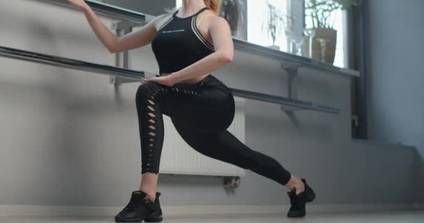 Çekici genç kadın dans salonundaki bale makinesinin yanında esneyip pratik yapıyor, sınıftaki seksi bayan dansçı, klasik bale egzersizleri, esnek kadın vücudu jimnastiği, 4k Dci 60p — Stok video