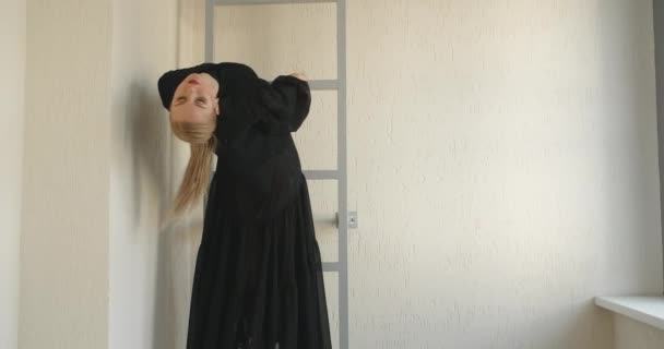 Bionda attraente ballerina con trucco in abito lungo nero fa esercizi di balletto e trucchi sulle scale, prove di danza classica, ballerina fa passi di danza in costume da palcoscenico, lezione di studio di danza — Video Stock