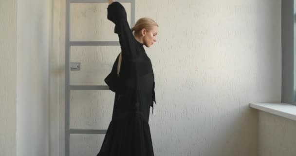 Blonde jolie danseuse avec maquillage en robe noire longue fait des exercices de ballet et des tours dans les escaliers, répétition de ballet, ballerine fait des pas de danse dans le costume de scène, leçon de studio de danse — Video