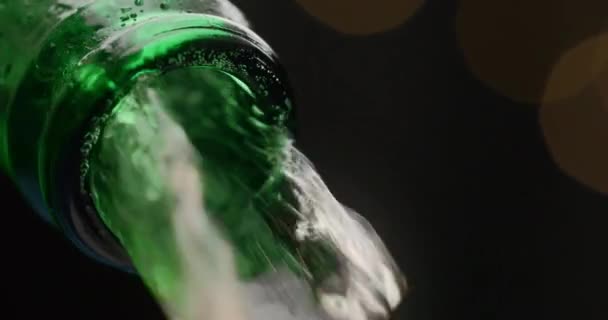 Arus bir mengalir melalui botol kaca hijau terbuka dalam video gerak lambat makro, bir dingin menuangkan keluar, aliran cairan, meja minuman, minuman alkohol, 4k 120p Prores HQ 10 bit — Stok Video