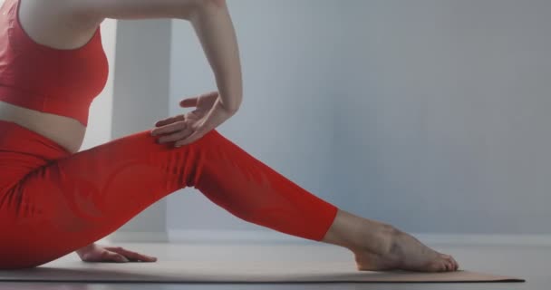 Attraktiv ung kvinna sträcker sig genom att böja sig framåt i sittande ställning på golvet på youga mattan, yoga klasser i slow motion, person gör fysiska övningar, stretching och gymnastik — Stockvideo