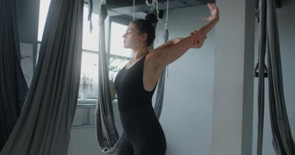 Attraktiv ung kvinna sträcker sig i fly yoga studio, yoga klasser i slow motion, person gör fysiska övningar, stretching och gymnastik, 4k DCI 60p Prores HQ — Stockvideo