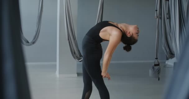 Attraktiv ung kvinna sträcker sig i fly yoga studio, yoga klasser i slow motion, person gör fysiska övningar, stretching och gymnastik, 4k DCI 60p Prores HQ — Stockvideo