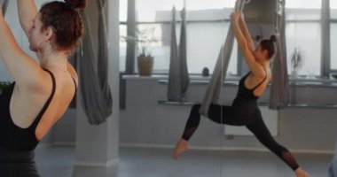 Çekici genç bir kadın, yoga hamağında yavaş çekimde sicim üzerinde oturur, esnek kadın akrobatik ve plastik egzersizler yapar, yoga ve esneme, 4k DCI 60p Prores 422