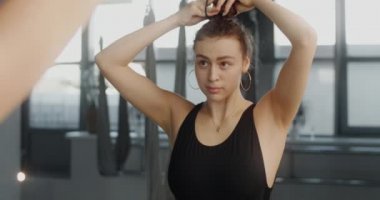 Çekici genç Kübalı kadın antrenmandan önce ayna duvarının önünde uzun kıvırcık saçlarıyla dans ediyor, bale stüdyosunda dans ediyor, kadın antrenman için hazırlanıyor, 4k 60p Prores 422
