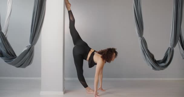 Attraente giovane cubana si trova su uno spago al muro in fly yoga studio al rallentatore, donna flessibile fa esercizi acrobatici e di plastica, yoga e stretching, 4k DCI 60p Prores 422 — Video Stock