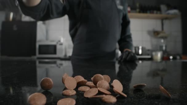 Chef-kok chocolatier giet melkchocolade druppels op de marmeren tafel in slow motion, grondstoffen voor het maken van snoep en chocolade, koken van de zoete desserts, het maken van chocoladerepen, Full HD 240fps Prores — Stockvideo