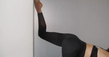 Çekici Kübalı genç kadın, yoga stüdyosunun duvarında yavaş çekimde sicimin üzerinde duruyor, esnek kadın akrobatik ve plastik egzersizler yapıyor, yoga ve esneme hareketleri yapıyor, 4k DCI 60p Prores 422