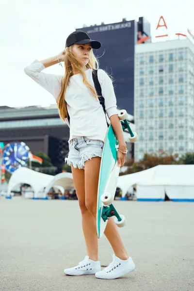Młoda kobieta pozowanie na ulicy z longboard, deskorolka, hipster stylu, odkryty z bliska portret, trampki, spodnie jeansowe — Zdjęcie stockowe