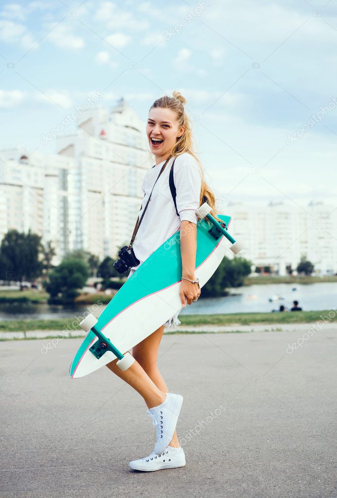 young woman posing in the street with longboard, skateboard, hipster style, outdoor close up portrait, sneakers, denim jeans