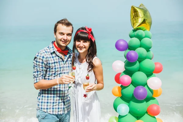 Couple standing near balloon tree on beach — Stock Photo, Image