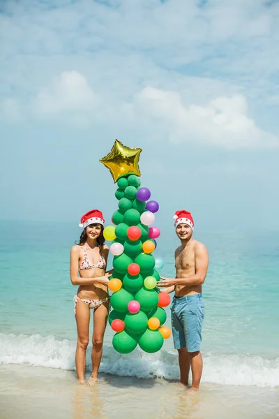 Pareja sosteniendo globo árbol en playa —  Fotos de Stock