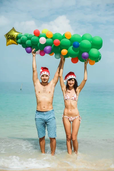 Pareja sosteniendo globo árbol en playa — Foto de Stock