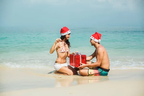 Pareja sentada con caja de regalo en la playa — Foto de Stock