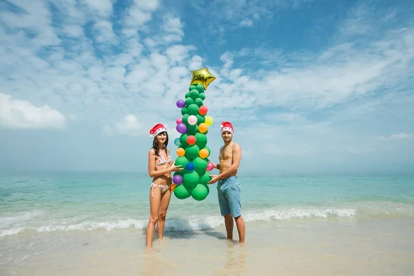 Pareja sosteniendo globo árbol en playa — Foto de Stock