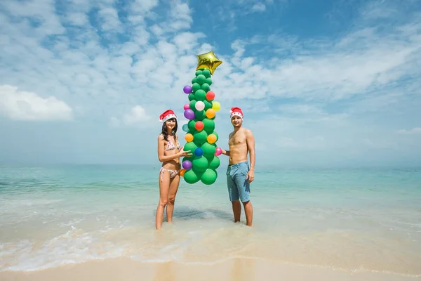 Casal segurando balão árvore na praia — Fotografia de Stock