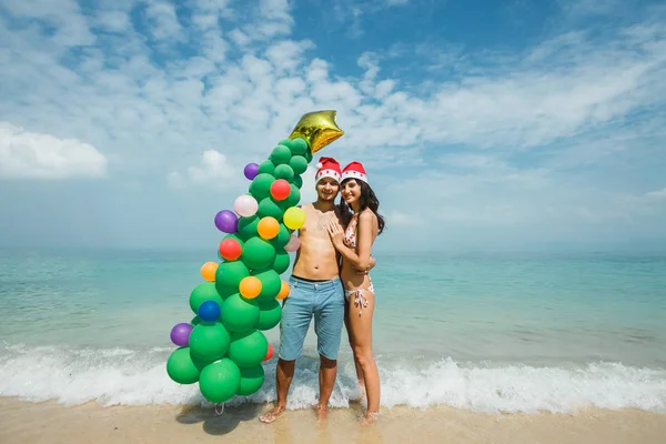 Couple standing with balloon tree on beach — Stock Photo, Image