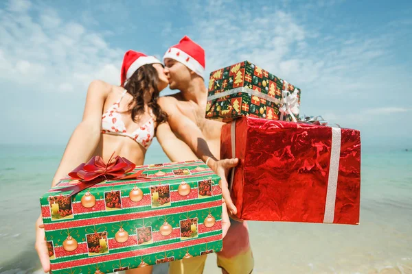 Couple standing with gift boxes on beach — Stock Photo, Image