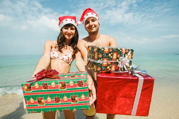 Pareja de pie con cajas de regalo en la playa — Foto de Stock