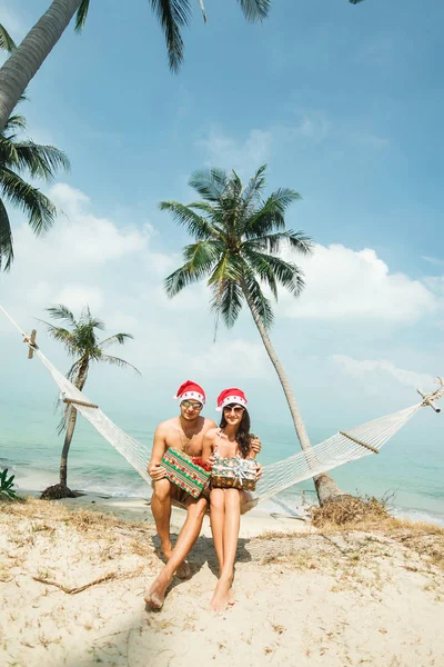 Couple sitting in hammock on beach — Stock Photo, Image