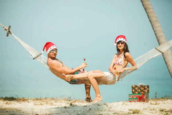 Pareja sentada en hamaca en Santa sombreros — Foto de Stock