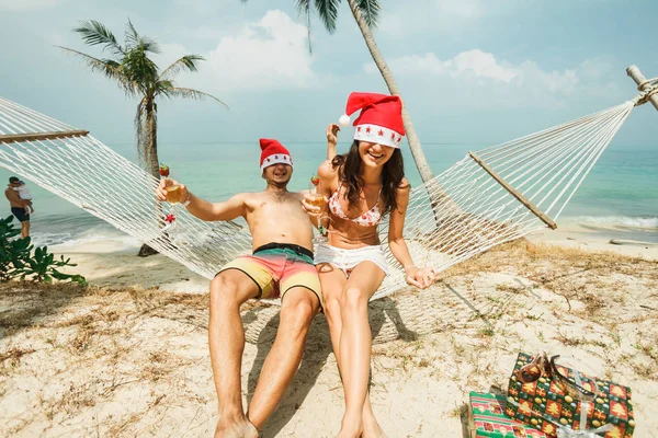 Pareja sentada en hamaca en Santa sombreros —  Fotos de Stock