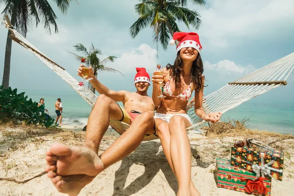 Pareja sentada en hamaca en Santa sombreros —  Fotos de Stock