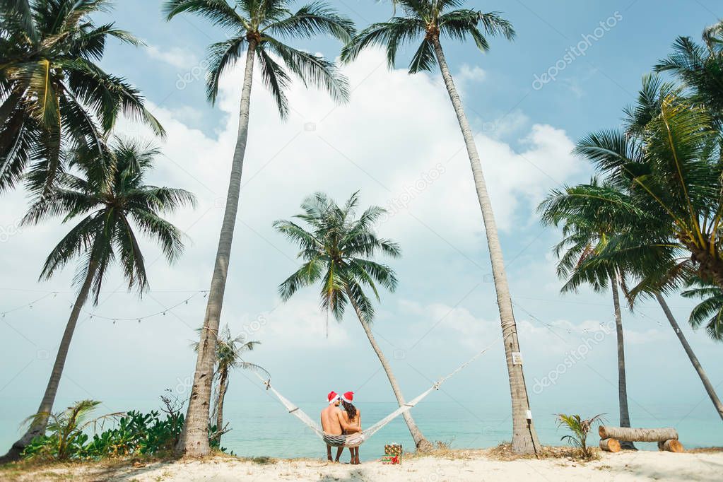 couple sitting in hammock on beach