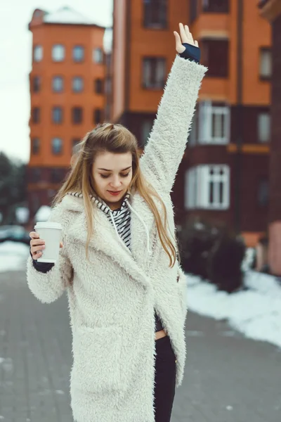 Молодая девушка позирует на улице, пьет кофе. — стоковое фото