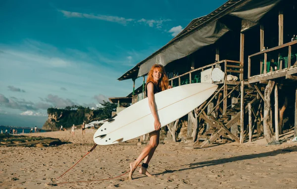 Surfer girl walking with board on the sandy beach. Surfer girl. Beautiful young woman at the beach. water sports. Healthy Active Lifestyle. Surfing. Summer Vacation. Extreme Sport. Bali