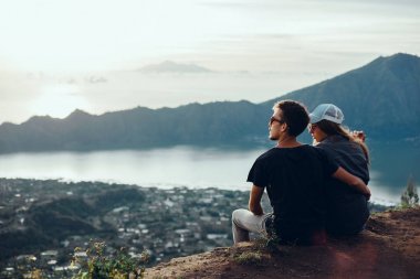Çift gezginler adam ve dağlar ve bulutlar hava görünümünü rahatlatıcı cliff üzerinde oturan bir bayan sevgi ve mutlu duygular yaşam tarzı kavramı seyahat. Genç aile seyahat aktif macera tatilleri, yenilikçi