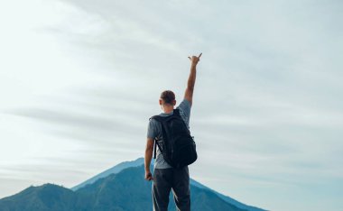 Genç yakışıklı adam eli kazanan yanardağ, güneşli sonbahar sabah üzerinde. Havada kaldırdı elleriyle mutlu hiker rock çam ormanı üzerinde durmak. Sun Vadisi'ne puslu ve sisli sabah üzerinde göster.