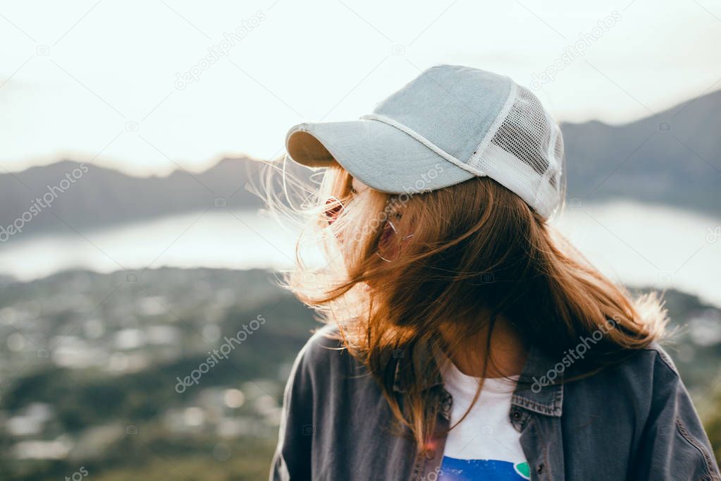 Woman traveler looking at volcano Rinjani, island Lombok. Indonesia.Young backpacker traveling along mountains, happy female walking discovering world, summer vacation concept, hand up winner, Bali