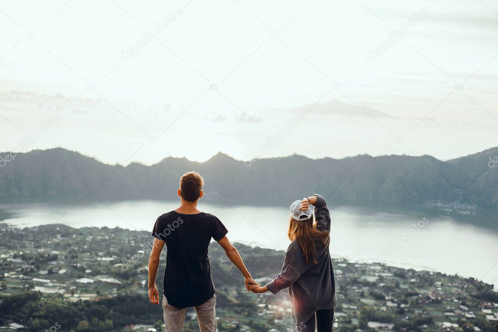 Couple travelers Man and Woman sitting on cliff relaxing mountains and clouds aerial view Love and Travel happy emotions Lifestyle concept. Young family traveling active adventure vacations,hipster