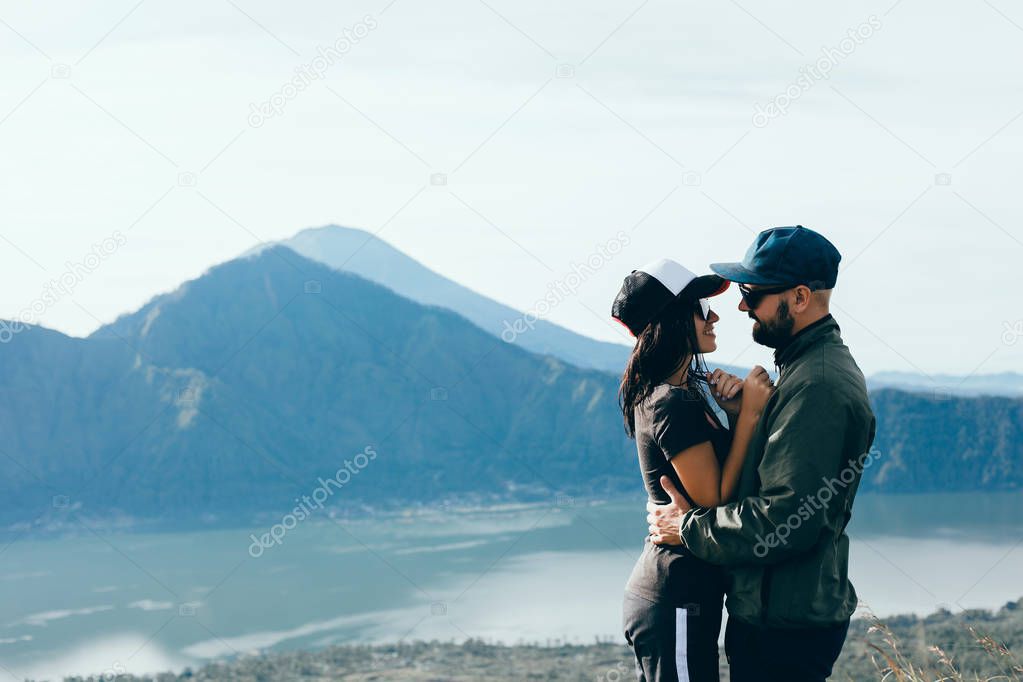 Couple travelers Man and Woman sitting on cliff relaxing mountains and clouds aerial view Love and Travel happy emotions Lifestyle concept. Young family traveling active adventure vacations,hipster