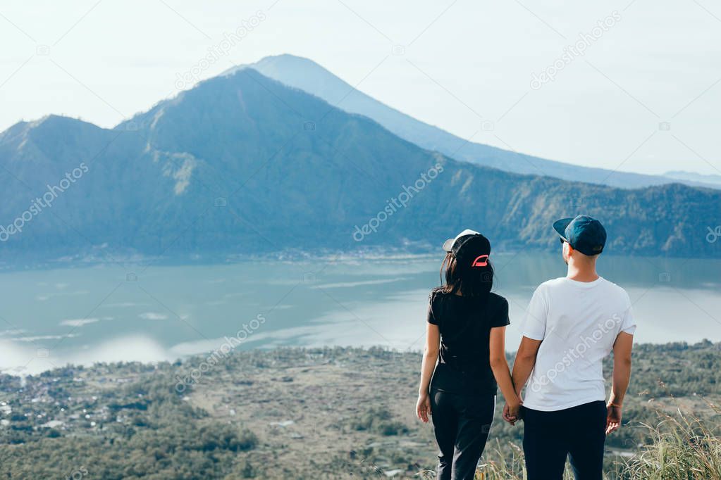 Couple travelers Man and Woman sitting on cliff relaxing mountains and clouds aerial view Love and Travel happy emotions Lifestyle concept. Young family traveling active adventure vacations,hipster