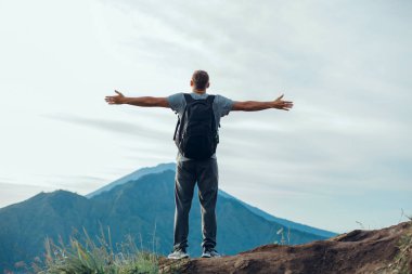 Genç yakışıklı adam eli kazanan yanardağ, güneşli sonbahar sabah üzerinde. Havada kaldırdı elleriyle mutlu hiker rock çam ormanı üzerinde durmak. Sun Vadisi'ne puslu ve sisli sabah üzerinde göster.