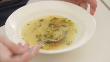 Bir çocuk bir çorba kaşığı ile yiyor.