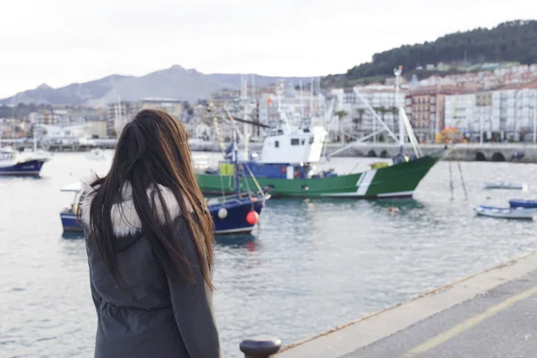 Esmer kız bakarak balıkçı limanı, küçük bir kıyı kenti, gemilerde de akşam deniz Harbor.