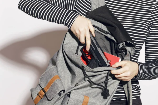 Girl hiding a gun in her school backpack. — Stock Photo, Image